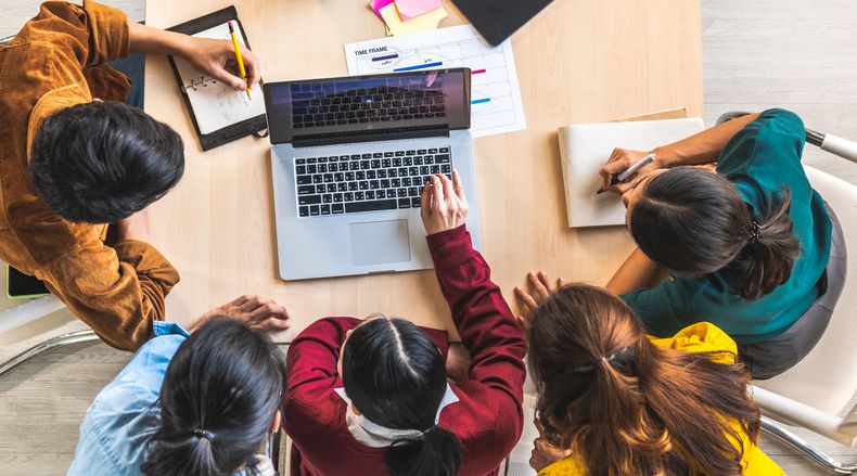 Students huddle around a laptop