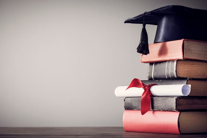 A graduation cap sits on top of a stack of books