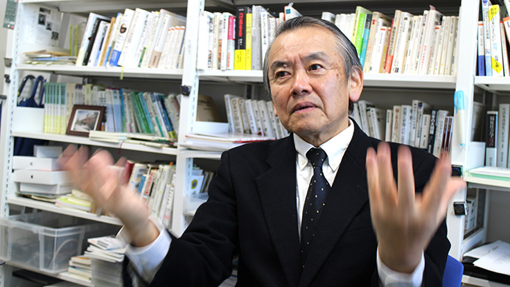 A person in a suit in front of a bookshelf